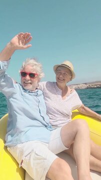 Cheerful senior couple smiling and enjoying a sunny day at sea on a bright yellow boat, embracing the active retired lifestyle and creating lasting memories together during their vacation