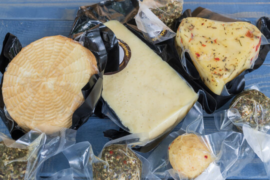 Traditional artisan Carpathian cheese selection in vacuum packaging displayed on a wooden background. Suitable for dairy, gourmet food and local production concepts.