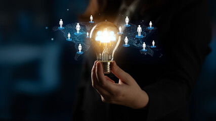 Business concept of networking and connections with glowing light bulb and digital icons of people over dark background, symbolizing bright ideas and collaborative growth. Entropy.