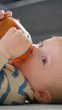 Midsequence playful lift of blonde infant reaching toward sofa in cozy living room with soft