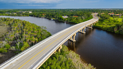 Fototapeta premium An aerial view of the Fort Hamer Bridge over the Manatee River in Bradenton, Florida. Afternoon rain showers fill the dark sky in the distance.