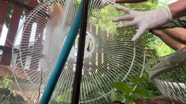Water from pipe flow freely cleaning dirt and dust form fan grill and blade at home outdoor