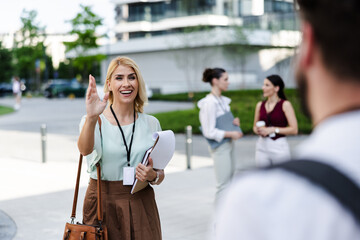 Cheerful businesswoman greeting colleagues in modern urban setting