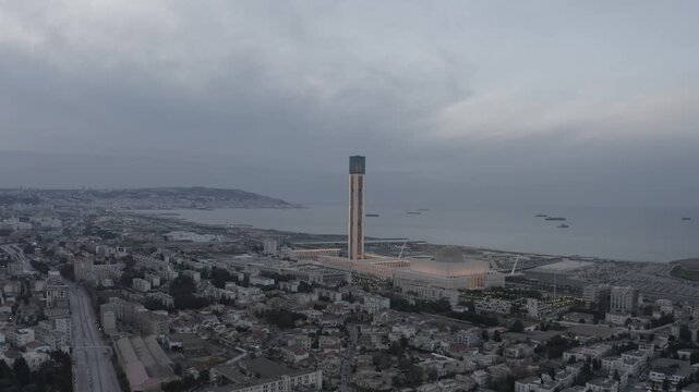 High-angle drone footage capturing the imposing scale of Djamaa el Djazair and its massive minaret dominating the Algerian capital's coastal landscape.