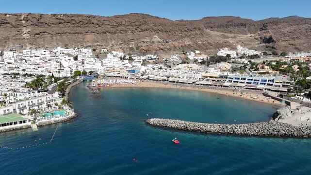 Aerial panorama flight towards Puerto de Mogan with beach, white houses and canal at Atlantic ocean on Canary Island Gran Canaria, Spain