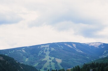 Fototapeta premium Summer Ski Resort Mountain with Green Slopes and Overcast Sky