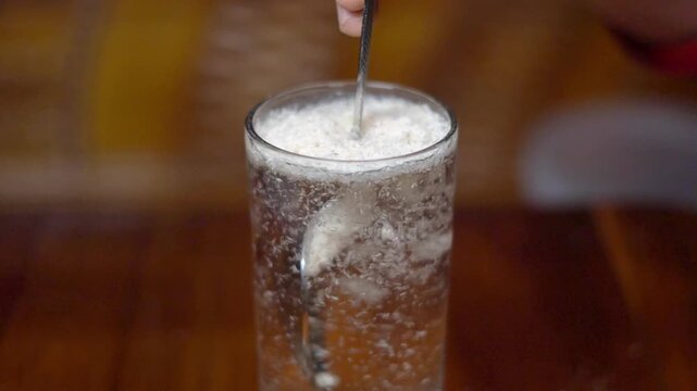 Stirring Psyllium Husk Powder in Glass of Water with Spoon Close Up. Preparing Isabgol Laxative Dietary Fiber Supplement Drink for Digestion. 