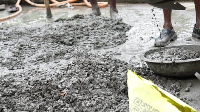 Indian Construction Workers Pouring Wet Cement Aggregate Mix on Rooftop.  Cinematic View of Liquid Cement Mix and Shovel Tool on Construction Floor. Concrete Slab Installation in an Indian House.
