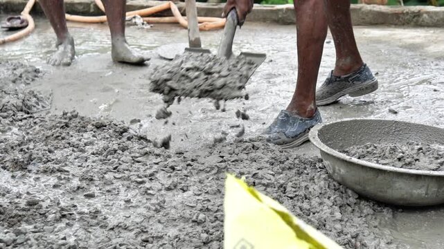 Indian Construction Workers Mixing Wet Cement Concrete by Hand at Building Site. Manual Concrete Mixing Process by Construction Laborers on Building Project.