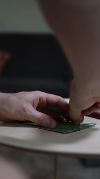 Vertical screen Close up of hand holding cigarette while scratching lottery ticket capturing risky habits gambling addiction hope for quick money financial desperation and chance