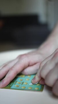 Vertical screen Close up of scratching lottery ticket with coin revealing hidden prize symbols during instant game capturing excitement hope luck potential jackpot and cash win