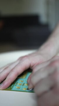 Vertical screen Close up of hands scratching lottery scratch card with coin revealing hidden symbols during instant win game hoping for cash prize luck and jackpot success