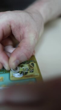 Vertical screen Close up of hands scratching lottery ticket with coin revealing hidden prize symbols hoping for instant cash reward jackpot lucky numbers and big win