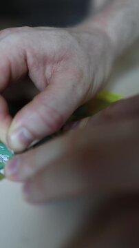 Vertical screen Macro close up of hand scratching lottery ticket with coin revealing hidden symbols hoping for instant win lucky numbers cash prize and jackpot success