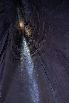 Underground waterfall flowing inside dark rocky cavern