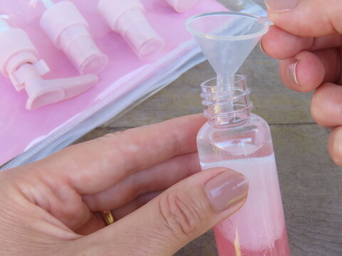 Woman hands holding a travel set plastic bottle with bi-phase oil inside. Female hands preparing travel set containers.