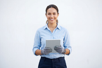 Obraz premium Smiling female electrician holding digital tablet against white wall