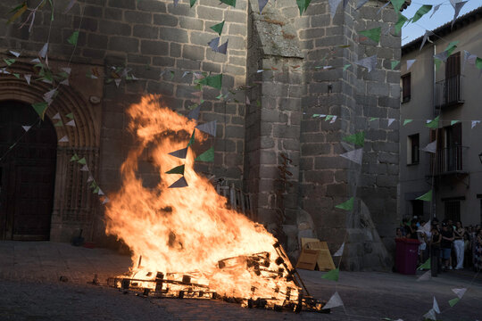 Traditional midsummer bonfire burning brightly outside the historic Church of San Juan Bautista during the Night of San Juan festival in Avila, Castile and Leon, Spain.