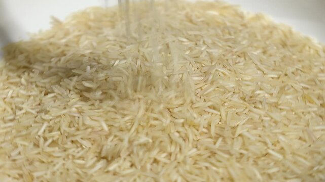 Pouring raw basmati rice into a pile, close up angle view