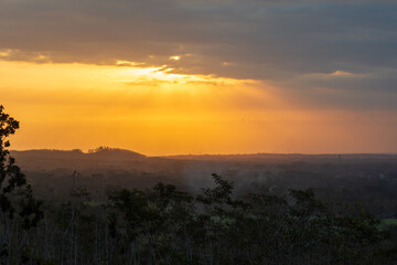 Obraz premium Beautiful golden sun rays breaking through dramatic clouds at sunset.