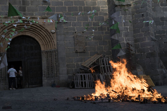 Traditional midsummer bonfire burning brightly outside the historic Church of San Juan Bautista during the Night of San Juan festival in Avila, Castile and Leon, Spain.