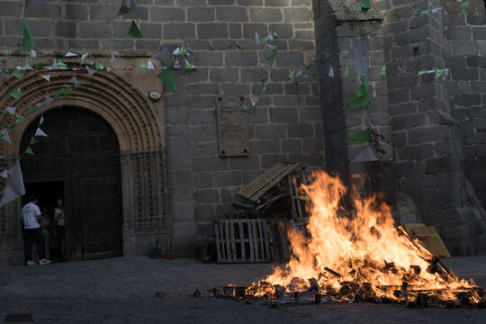 Traditional midsummer bonfire burning brightly outside the historic Church of San Juan Bautista during the Night of San Juan festival in Avila, Castile and Leon, Spain.