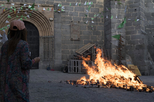 Traditional midsummer bonfire burning brightly outside the historic Church of San Juan Bautista during the Night of San Juan festival in Avila, Castile and Leon, Spain.