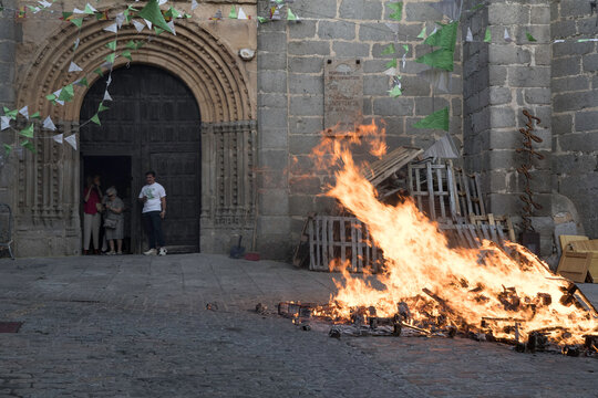 Traditional midsummer bonfire burning brightly outside the historic Church of San Juan Bautista during the Night of San Juan festival in Avila, Castile and Leon, Spain.