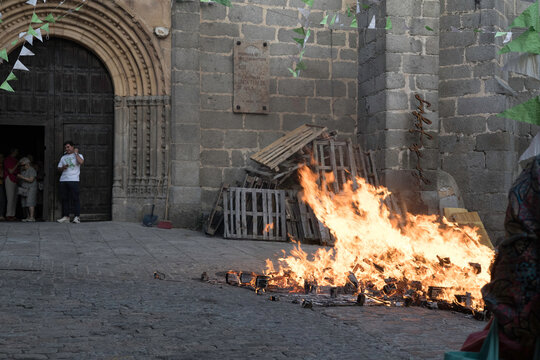Traditional midsummer bonfire burning brightly outside the historic Church of San Juan Bautista during the Night of San Juan festival in Avila, Castile and Leon, Spain.