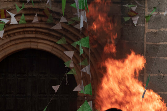 Traditional midsummer bonfire burning brightly outside the historic Church of San Juan Bautista during the Night of San Juan festival in Avila, Castile and Leon, Spain.
