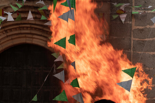 Traditional midsummer bonfire burning brightly outside the historic Church of San Juan Bautista during the Night of San Juan festival in Avila, Castile and Leon, Spain.