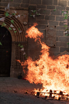 Traditional midsummer bonfire burning brightly outside the historic Church of San Juan Bautista during the Night of San Juan festival in Avila, Castile and Leon, Spain.