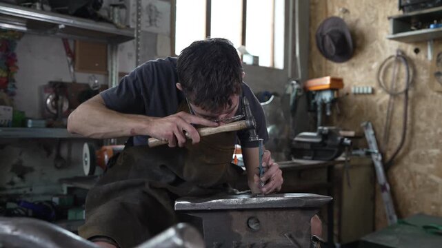 Skilled blacksmith engraving metal on an anvil