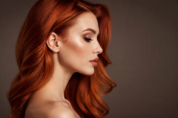 Fototapeta premium Redheaded woman posing in profile on neutral background