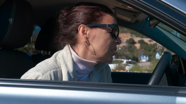 Tired woman falling asleep while driving a car. Dangerous situation showing a drowsy woman wearing sunglasses falling asleep at the steering wheel, succumbing to fatigue while driving