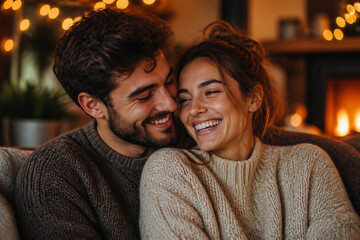 Fototapeta premium Couple laughing together on couch by fireplace in cozy home