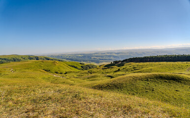 Fototapeta premium Layers of green mountains and hills in the haze during sunset. Panoramic View of Green hills and Meadow.