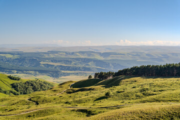 Obraz premium Layers of green mountains and hills in the haze during sunset. Panoramic View of Green hills and Meadow.