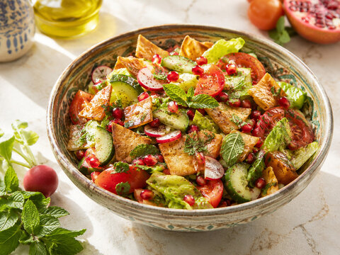 Syrischer Fattoush-Salat mit knusprigem Fladenbrot, Tomaten, Gurken, Radieschen, Granatapfel und frischer Minze &ndash; farbenfrohe levantinische Vorspeise auf orientalischer Keramik.