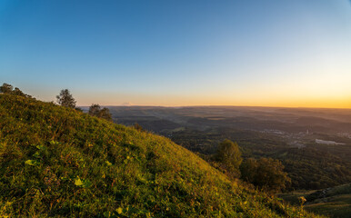 Fototapeta premium Layers of green mountains and hills in the haze during sunset. Panoramic View of Green hills and Meadow.