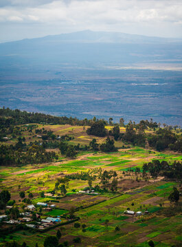 View of the agricultural landscape with patchwork fields, scattered trees, and small houses in the valley near Lake Nakuru National Park, Nakuru, Nakuru County, Kenya.