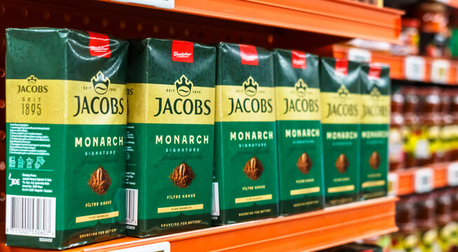 Coffee packaging displayed on a supermarket shelf featuring multiple boxes of Jacobs Monarch coffee with green and red branding in a retail environment