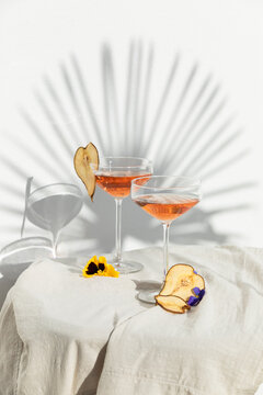 Two rose wine glasses with summer cocktails and dried fruit appetizers
