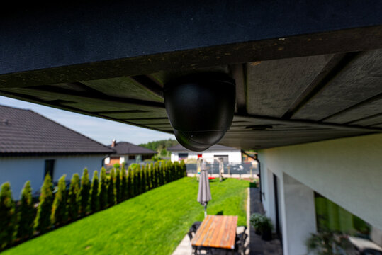 Dome security camera monitoring modern home backyard