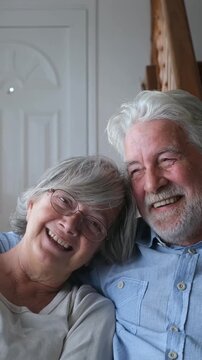 Adorable senior couple sitting together at home laughing and smiling in a moment of complicity