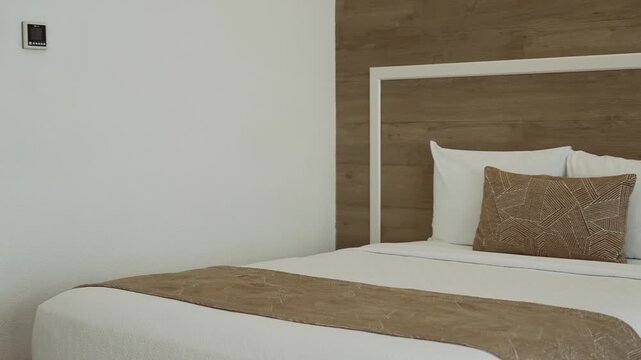 Close up of a beautifully made bed featuring clean and elegantly arranged pillows
