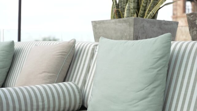Close up of a stylish sofa featuring a collection of neat blue-gray striped and solid cushions
