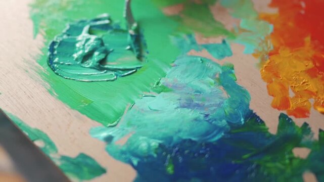 Artist unrecognizable female mixing oil and acrylic paint on palette with spatula in 4K Ultra HD footage.
