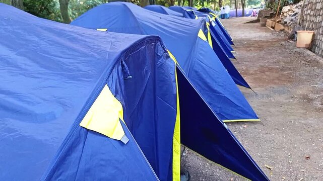 Row of blue camping tents pitched in a row at an outdoor campsite