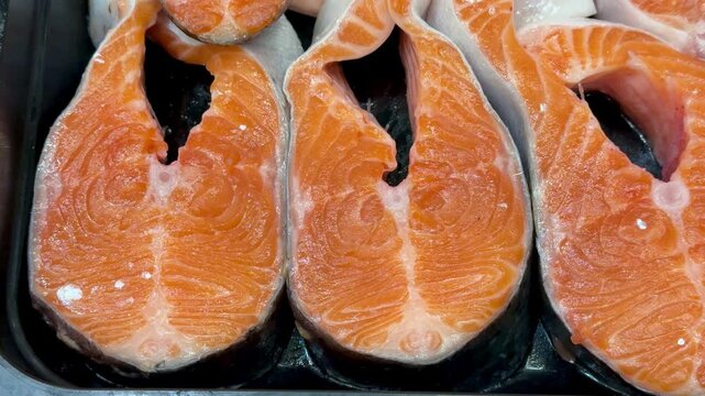 Steaks of chilled Atlantic salmon from frozen raw materials on a substrate for sale in a supermarket. Close-up